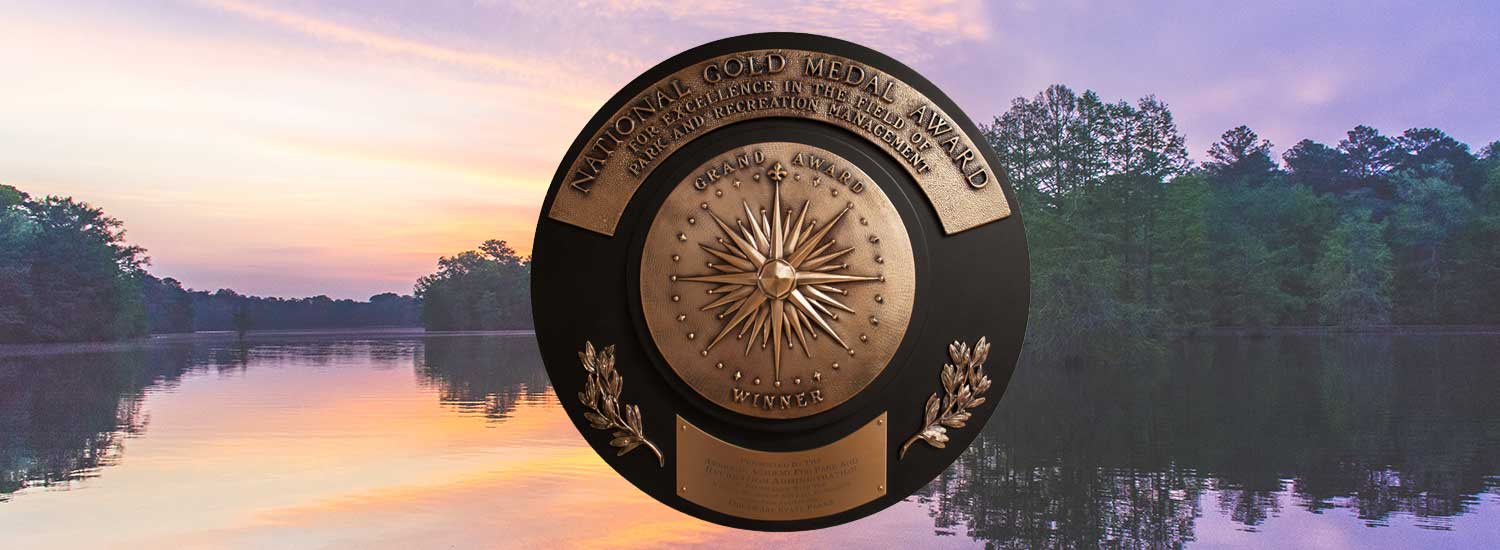 Gold Medal seal in front of people kayaking on a pond